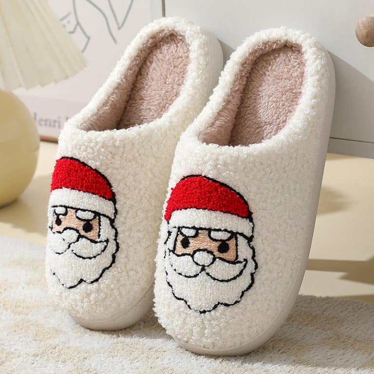 Cozy Christmas slippers with shearling texture resting by a fireplace with candles and chunky knits
